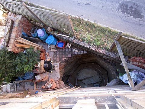 Вид на яму с верхего этажа. Внизу виден силует новой кирпичной стены.