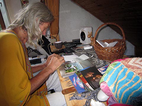 Istvan Sky в жёлтой курте за рабочим столом на верхнем этаже дома ставит автографы на альбомных дисках.