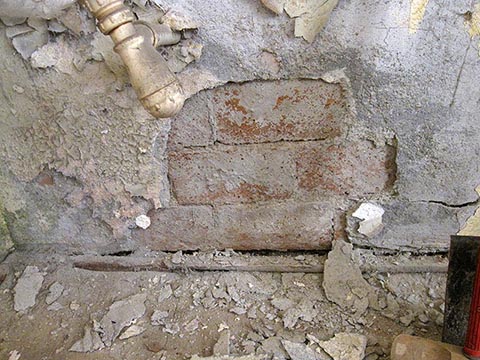 Пропадающая от сырости стена выложена просто на полу.