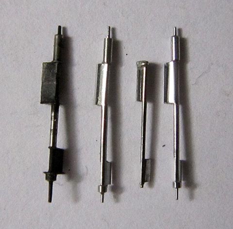 Herstellung der Unruhachse. Drei gefertigte Unruhwellen mit abgerundeter Palettenseite neben der gebrochenen. Antike Tischuhr mit Spindelhemmung.