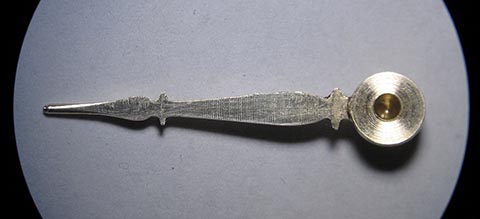 Herstellung des Minutenzeigers. Flache Seite mit gebohrter Öffnung für das Minutenrohr. Antike Tischuhr mit Spindelhemmung.