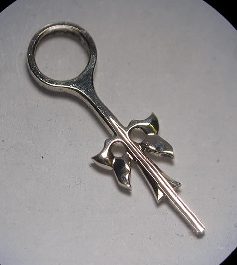 Herstellung des Stundenzeigers. Endgültig polierter und fertiger goldener Stundenzeiger. Antike Tischuhr mit Spindelhemmung.