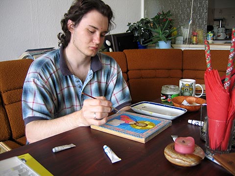 Alexander Babel am Tisch, wie er ein Ikonenbild zum Jubiläum von Vater Dionysius malt.