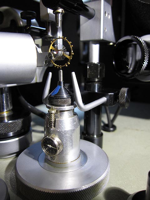 Jean Widmer-Steiner zum Auswuchten einer Schraubenunruh Typ 1. Nahaufnahme des Auswuchtvorgangs der Unruh im Gerät. Tiefenmessgerät für die Bohrung.