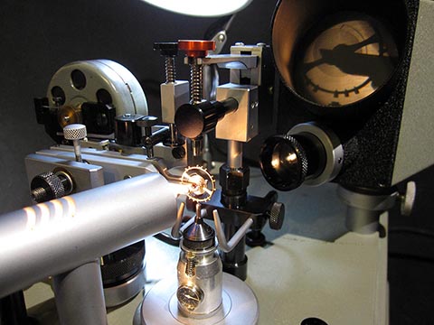 Jean Widmer-Steiner zum Auswuchten einer Schraubenunruh Typ 1. Mithilfe eines Lichtstrahls wird die schwarze Silhouette der Unruh auf einen kleinen Bildschirm projiziert.