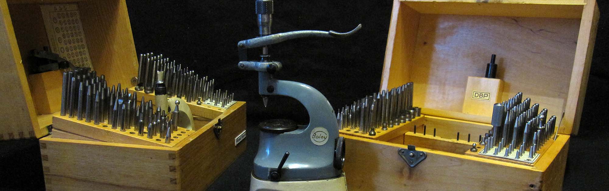 BOLEY-Triebnietmaschine, Vorrichtung zum Aufsetzen von Zeigern, Presse. Zwei Kästen mit Punzen.