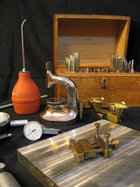 Spezial-Uhrmacherwerkzeug: Vorrichtung zum Einpressen von Steinen, Kasten mit Punzen, Eingriffszirkel, Blasebalg, Zinnblock, Mikrometer u. a.